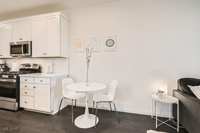 kitchen featuring appliances with stainless steel finishes, light countertops, baseboards, and white cabinetry