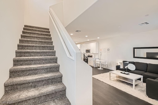 staircase with visible vents, wood finished floors, and recessed lighting