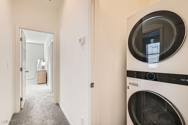 laundry room featuring carpet floors, stacked washing maching and dryer, laundry area, and baseboards