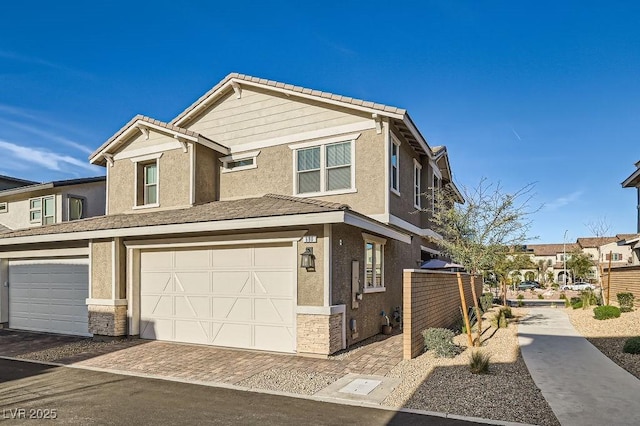 view of front of house featuring a garage, stone siding, a tiled roof, and stucco siding