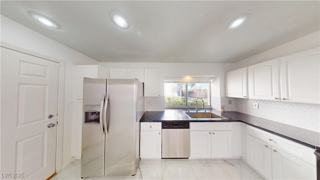 kitchen with marble finish floor, stainless steel appliances, dark countertops, and a sink