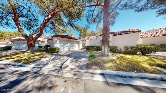 mediterranean / spanish-style house with a garage, driveway, a tile roof, and stucco siding