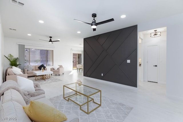 living room with an accent wall, visible vents, a ceiling fan, and recessed lighting