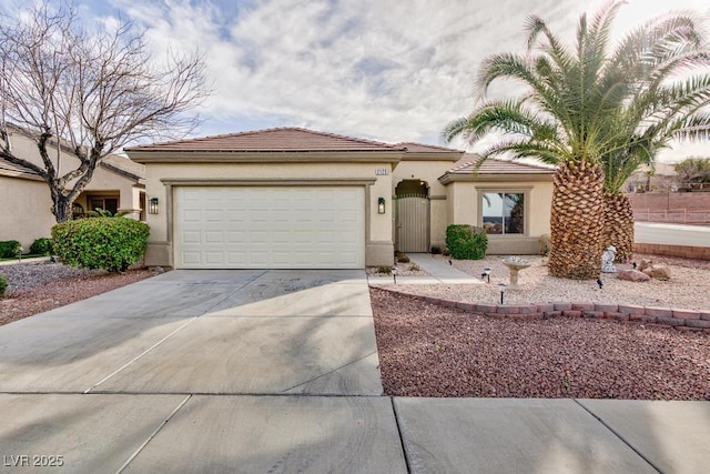 mediterranean / spanish-style house with a garage, concrete driveway, a tile roof, and stucco siding