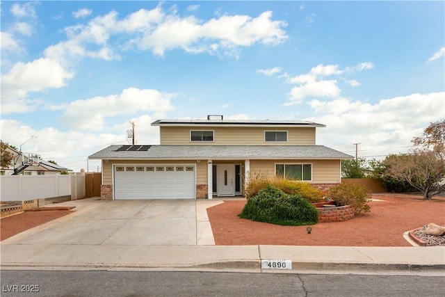 traditional-style home with roof mounted solar panels, fence, concrete driveway, and brick siding