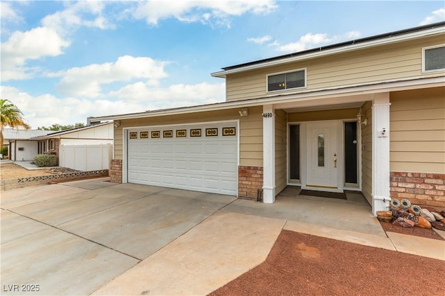 view of front of home with a garage, concrete driveway, brick siding, and roof mounted solar panels