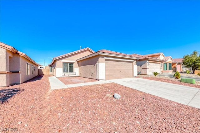 view of front of property featuring concrete driveway, a tiled roof, an attached garage, fence, and stucco siding