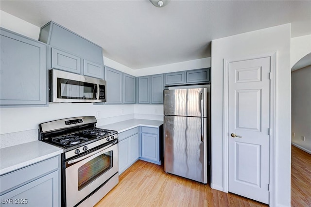 kitchen featuring appliances with stainless steel finishes, gray cabinets, light countertops, and light wood-style floors