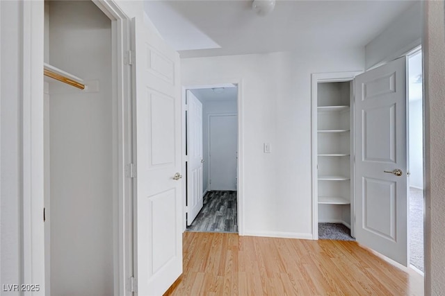 unfurnished bedroom featuring light wood finished floors, baseboards, and a closet