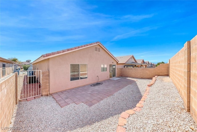 back of house featuring a patio area, a fenced backyard, a gate, and stucco siding