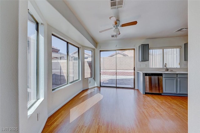 interior space featuring light wood-style flooring, a sink, visible vents, and baseboards