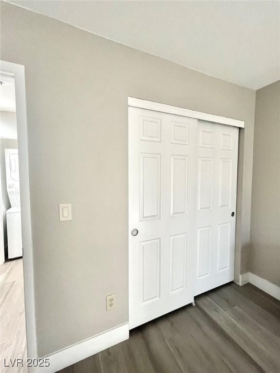 6250 W Flamingo Rd Unit 103, Las Vegas, NV 89103 - unfurnished bedroom featuring baseboards, stacked washer / dryer, wood finished floors, and a closet