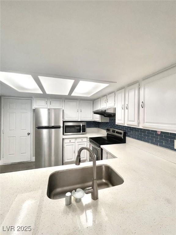 6250 W Flamingo Rd Unit 103, Las Vegas, NV 89103 - kitchen with appliances with stainless steel finishes, a sink, under cabinet range hood, white cabinets, and light stone countertops