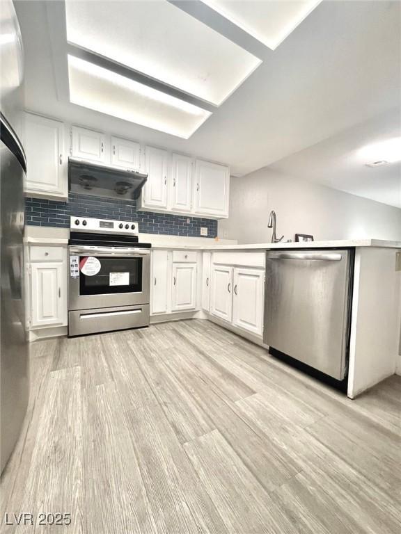6250 W Flamingo Rd Unit 103, Las Vegas, NV 89103 - kitchen featuring stainless steel appliances, under cabinet range hood, light countertops, white cabinetry, and tasteful backsplash