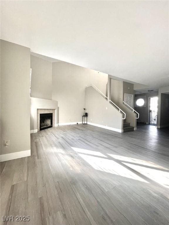 6250 W Flamingo Rd Unit 103, Las Vegas, NV 89103 - unfurnished living room with wood finished floors, stairway, baseboards, and a tile fireplace