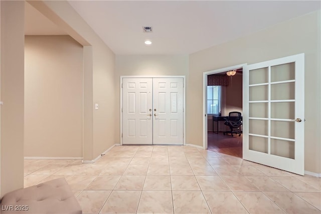 empty room with light tile patterned floors, french doors, visible vents, and baseboards