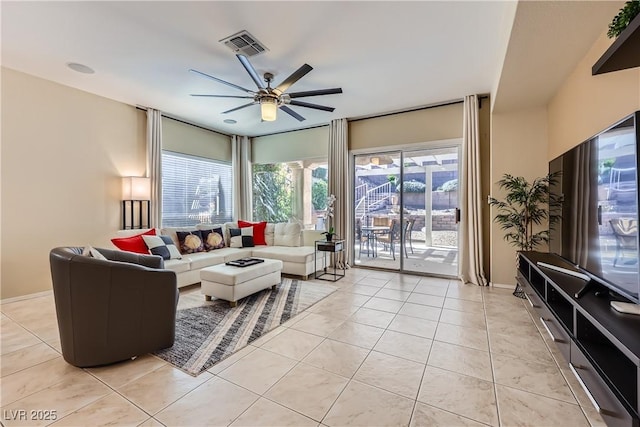 living area featuring light tile patterned floors, baseboards, visible vents, and a ceiling fan