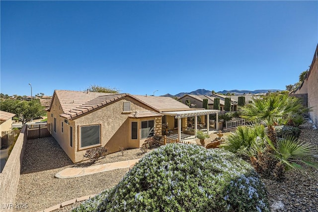 exterior space with a patio area, a fenced backyard, a tiled roof, and stucco siding