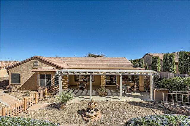 rear view of house with a patio area, a tile roof, fence, and stucco siding