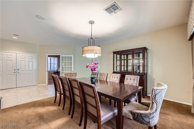 dining area with baseboards, light tile patterned flooring, visible vents, and light colored carpet