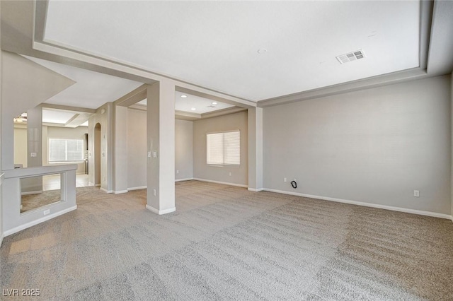 empty room featuring arched walkways, baseboards, visible vents, and carpet flooring