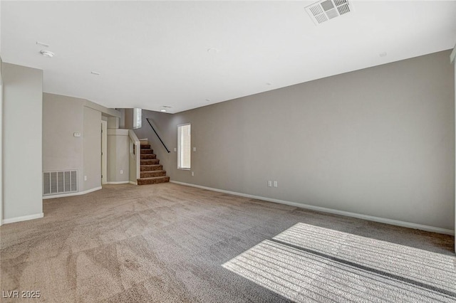 carpeted empty room with stairs, visible vents, and baseboards