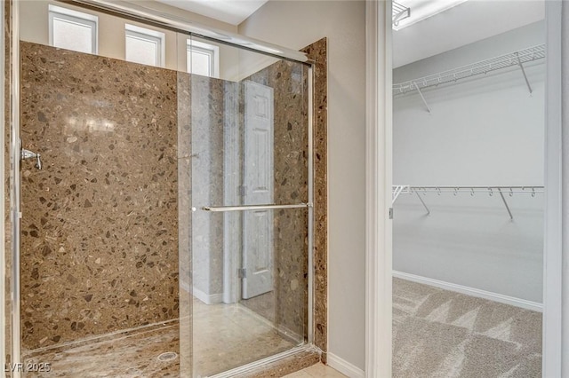 bathroom featuring a shower stall and a walk in closet