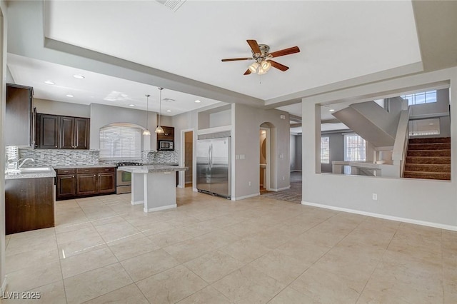 kitchen with dark brown cabinetry, stainless steel appliances, a sink, light countertops, and backsplash