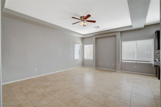 unfurnished room with light tile patterned floors, baseboards, visible vents, and a raised ceiling