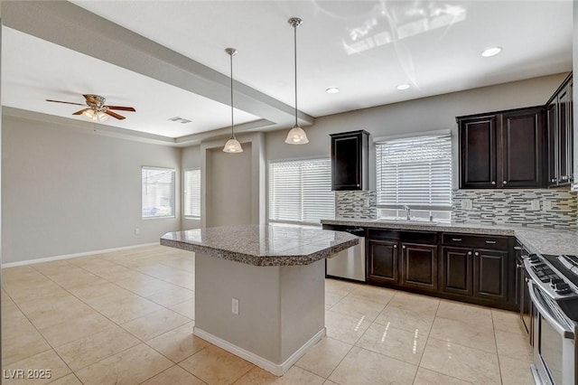 kitchen featuring baseboards, appliances with stainless steel finishes, a center island, backsplash, and light tile patterned flooring