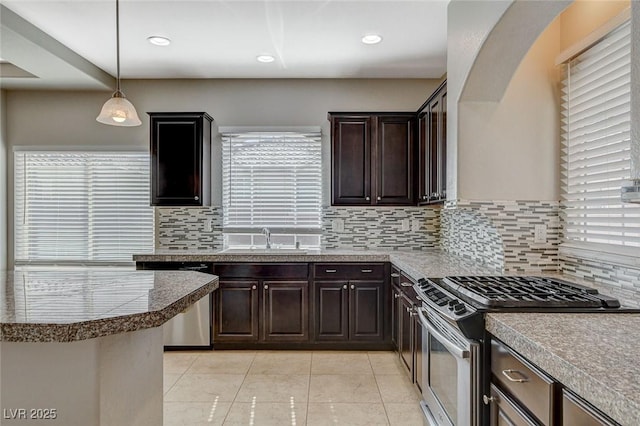 kitchen featuring light tile patterned floors, dark brown cabinetry, stainless steel appliances, a sink, and hanging light fixtures