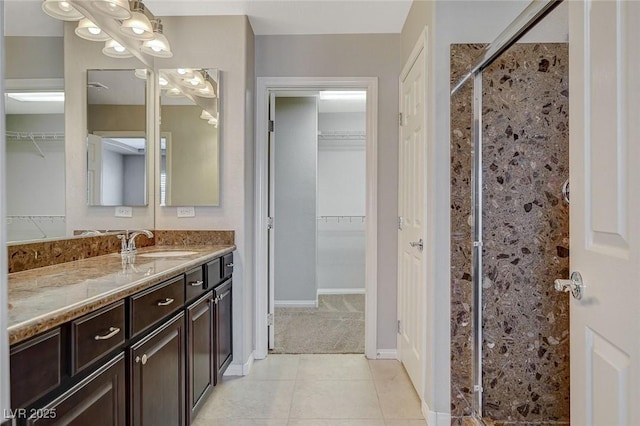 bathroom featuring a shower stall, a walk in closet, tile patterned flooring, and vanity