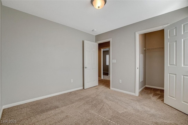 unfurnished bedroom with a spacious closet, a closet, carpet flooring, and baseboards