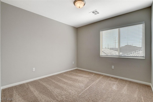 spare room featuring carpet, visible vents, and baseboards