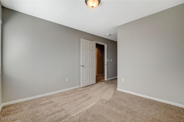 unfurnished room featuring light colored carpet and baseboards