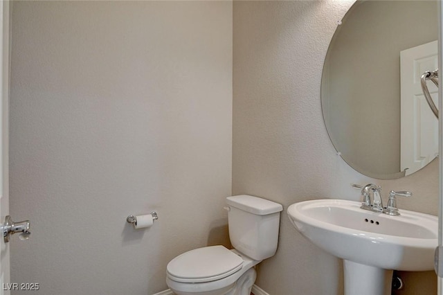 bathroom featuring baseboards, a sink, and toilet