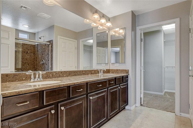 full bath with a spacious closet, a sink, visible vents, and a shower stall