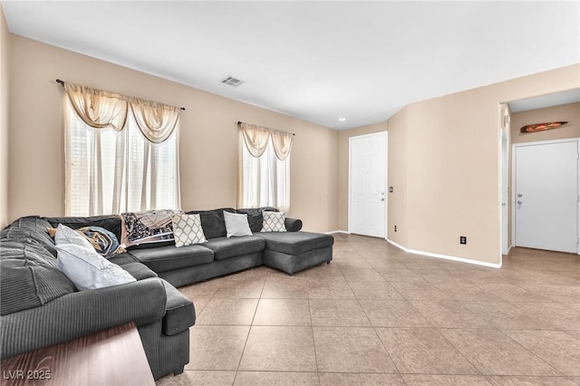 living area featuring light tile patterned floors, visible vents, and baseboards