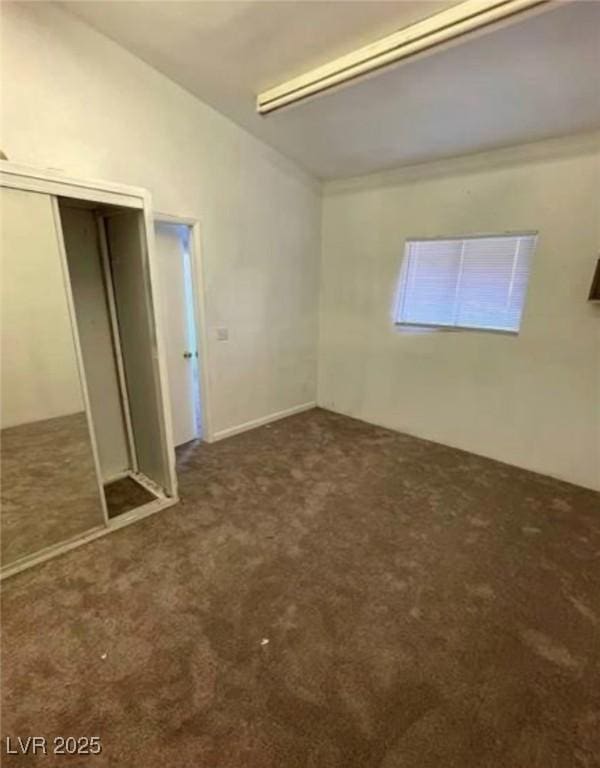 unfurnished bedroom with vaulted ceiling, a closet, and carpet