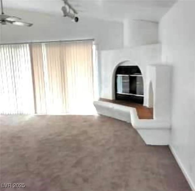 unfurnished living room with carpet, rail lighting, and ceiling fan