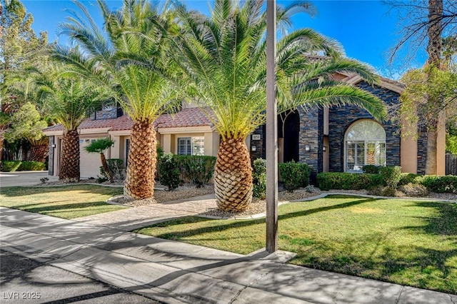 view of front of property with stucco siding, a tiled roof, concrete driveway, and a front yard