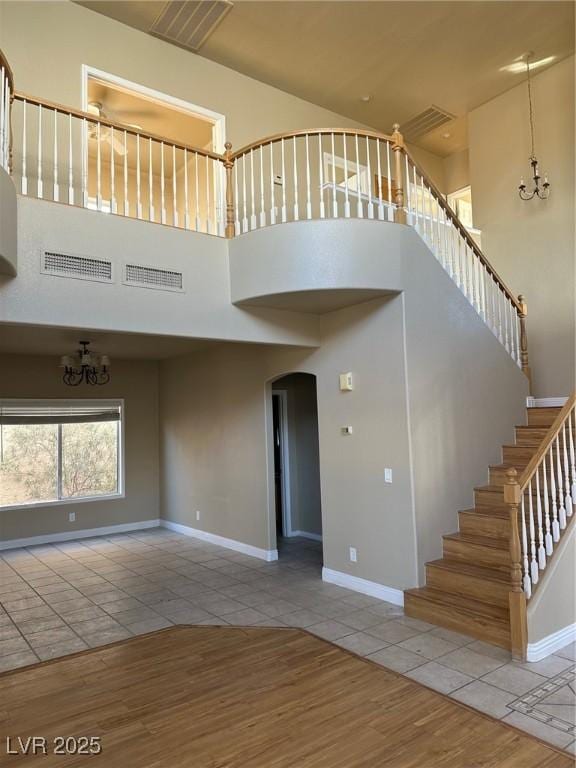 unfurnished living room featuring baseboards, a high ceiling, a chandelier, and tile patterned floors