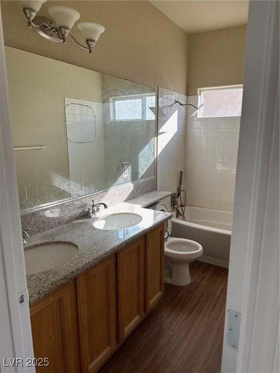 full bath with double vanity, wood finished floors, a sink, and toilet