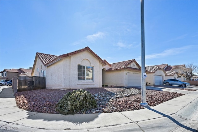 view of front of home featuring driveway, an attached garage, a tile roof, and stucco siding