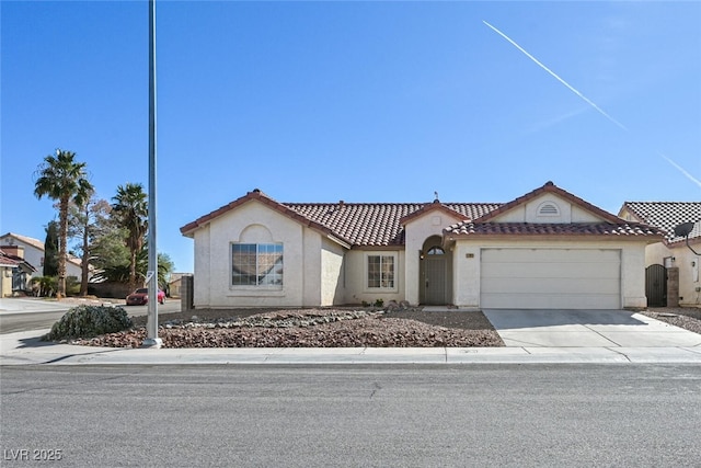 mediterranean / spanish home with an attached garage, a tile roof, concrete driveway, and stucco siding