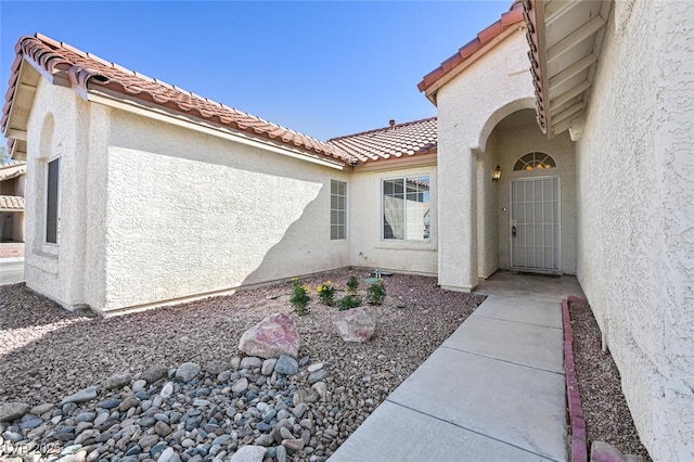 entrance to property with a tiled roof and stucco siding