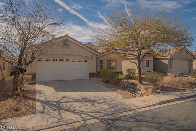 ranch-style home with a garage, concrete driveway, a tile roof, and stucco siding