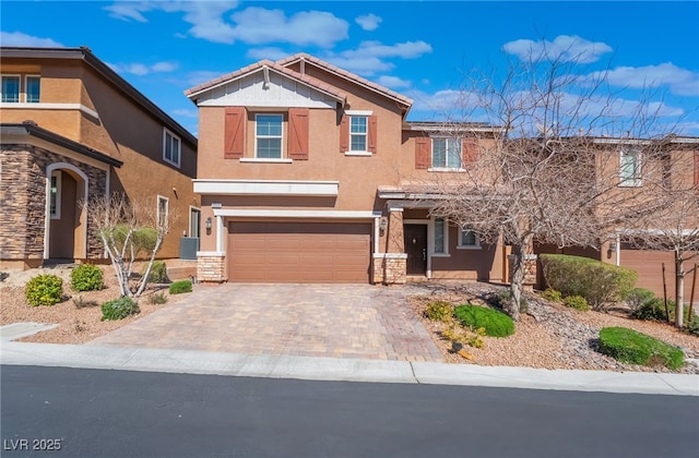 view of front of house featuring stone siding, an attached garage, decorative driveway, central AC, and stucco siding