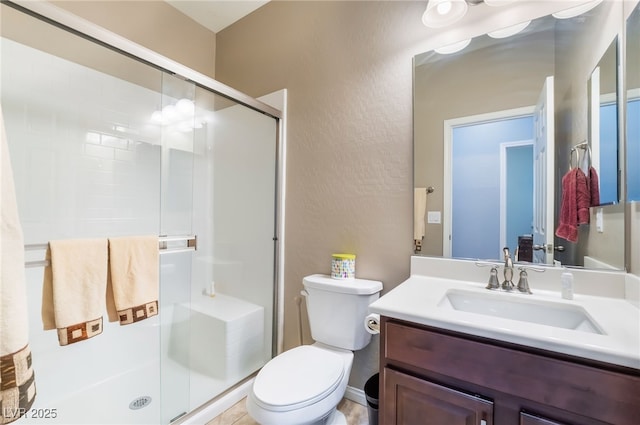 full bathroom with toilet, a textured wall, a shower stall, and vanity