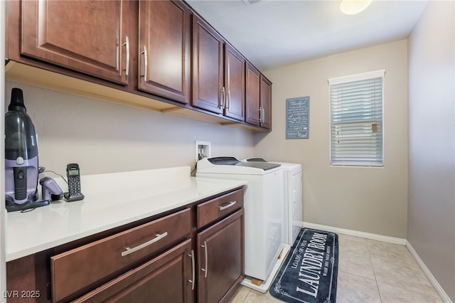 laundry room with light tile patterned flooring, washing machine and dryer, cabinet space, and baseboards